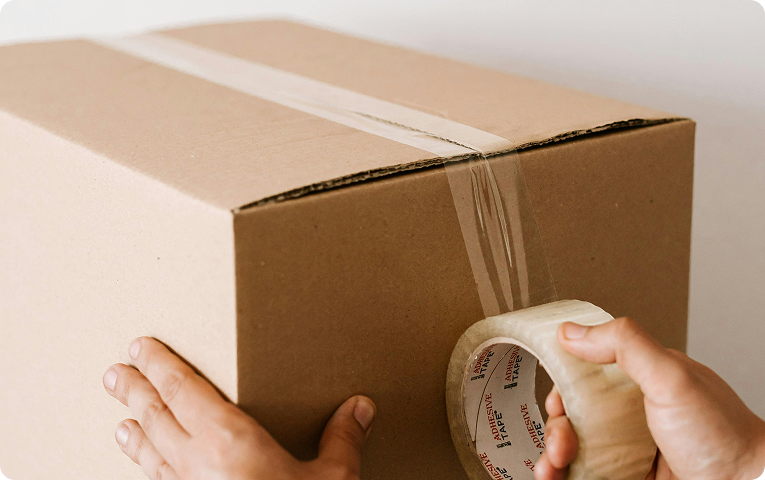 Person taping a cardboard box shut.